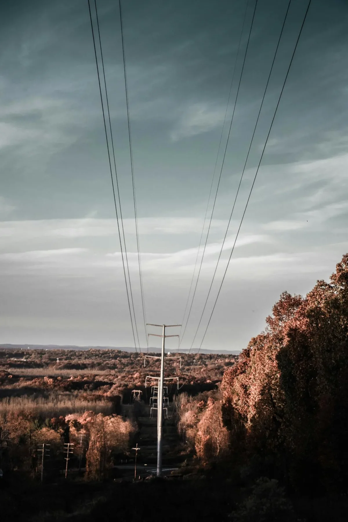 Power lines crossing a rocky landscape beneath dark clouds
