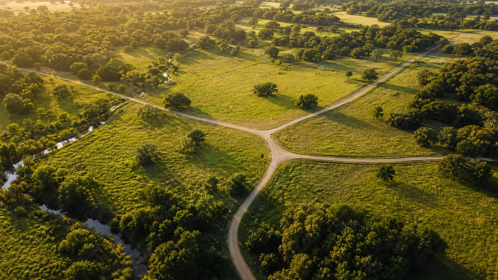 Aerial view of rural roads converging around open land at golden hour